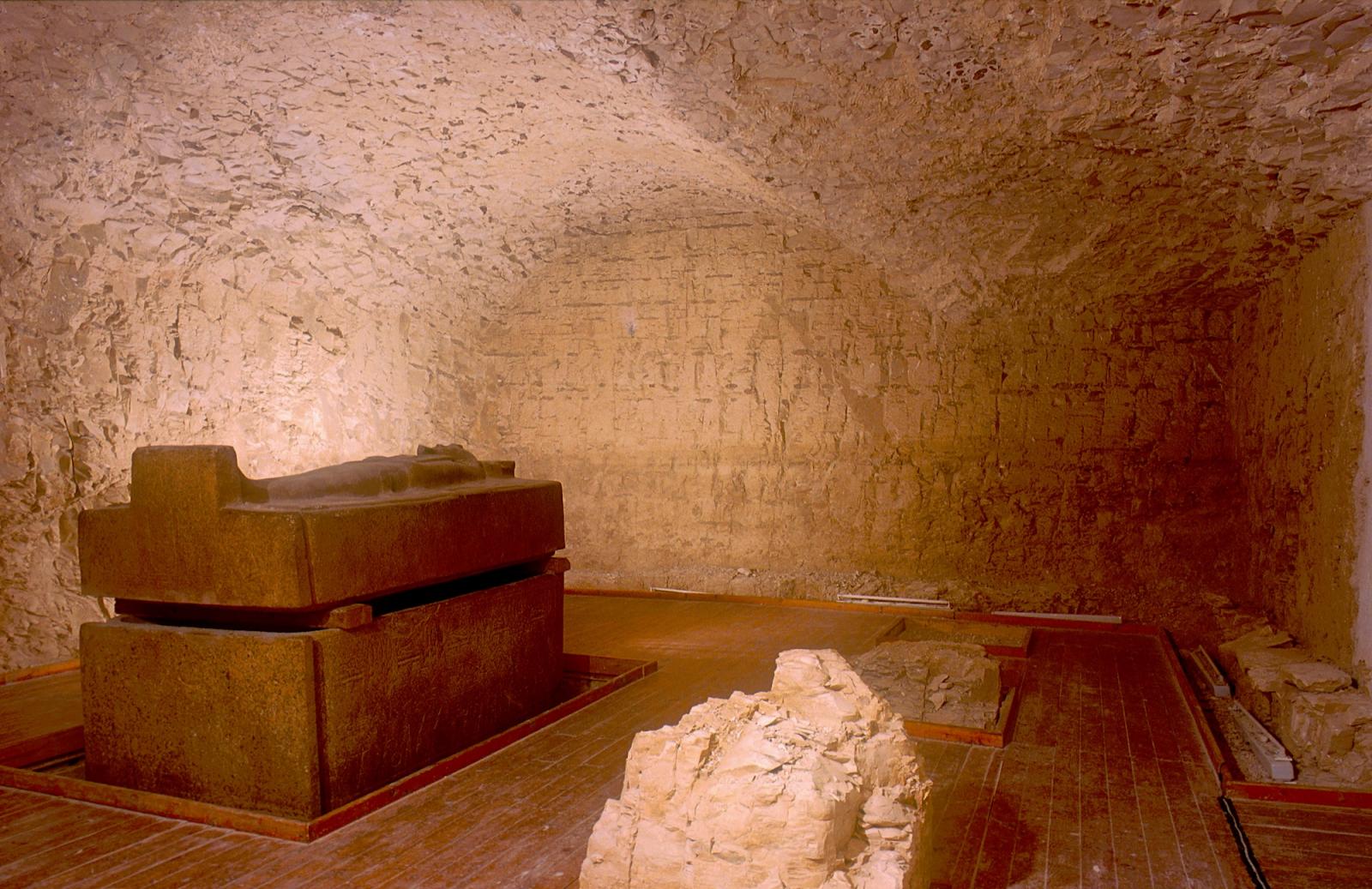Sarcophagus in undecorated burial chamber with modern flooring.